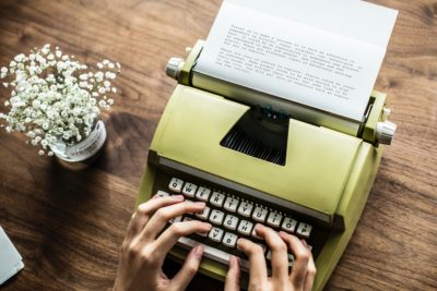 Someone typing on a pale green typewriter