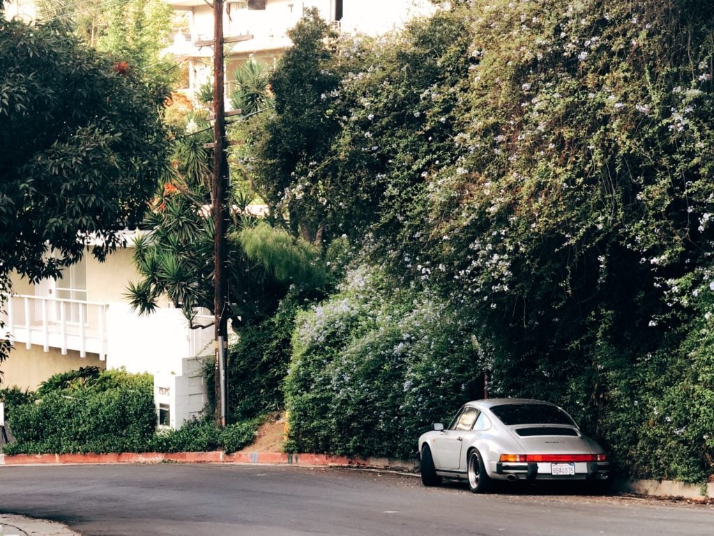 A classic Porsche 911 parked next to some trees